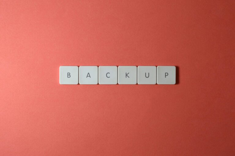 Free Close-up of keyboard keys spelling 'BACKUP' placed on a coral-colored surface. Stock Photo