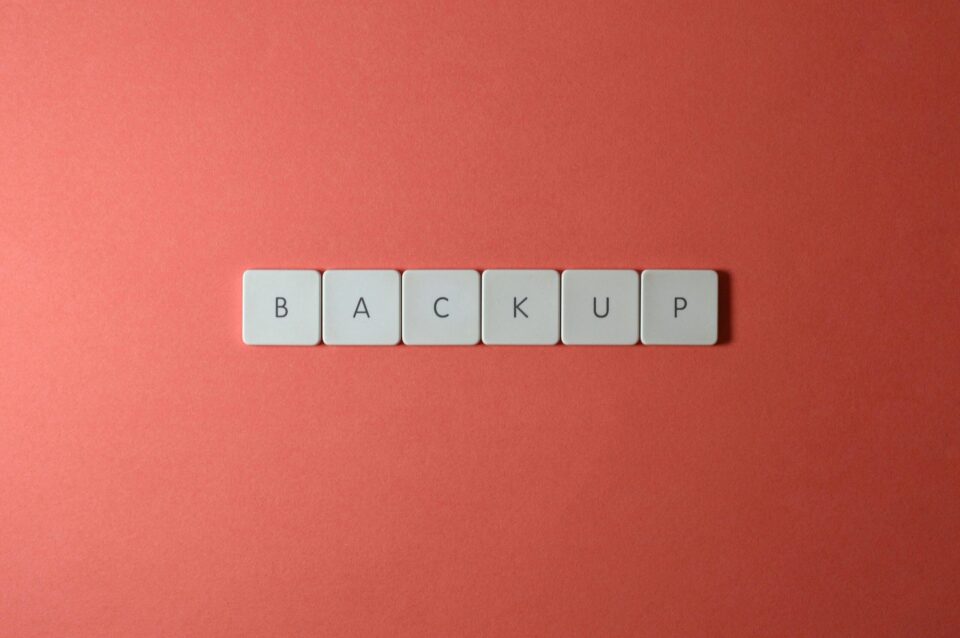 Free Close-up of keyboard keys spelling 'BACKUP' placed on a coral-colored surface. Stock Photo